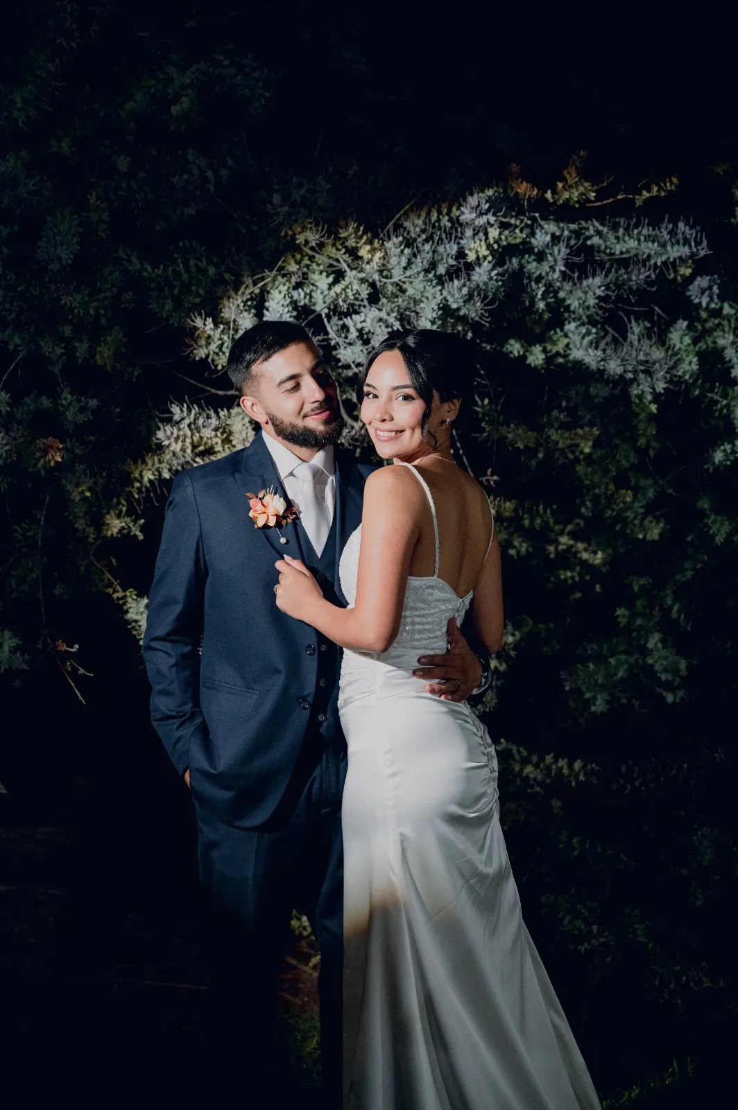 Novios abrazados de noche entre la vegetación