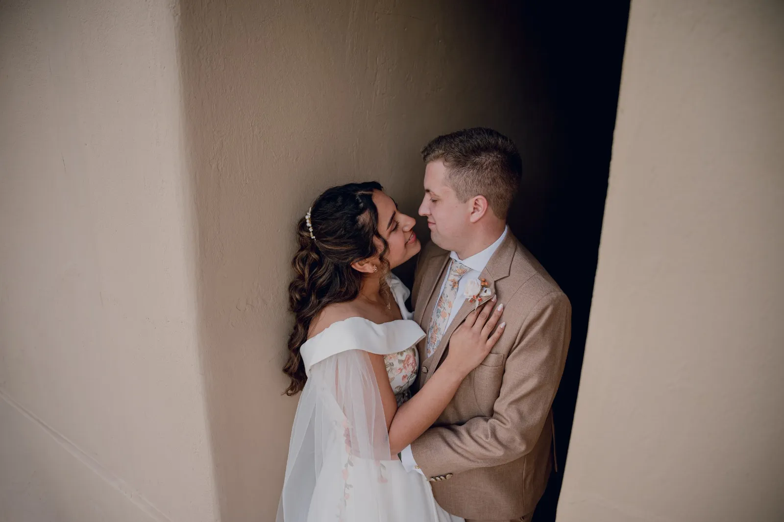 Novios besándose en un portal de paredes color arena