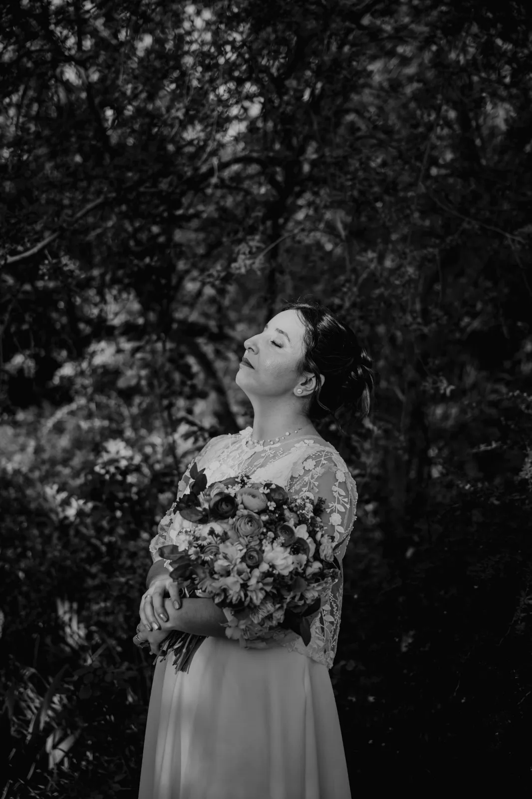 Novia con la mirada hacia arriba, retrato en blanco y negro entre árboles