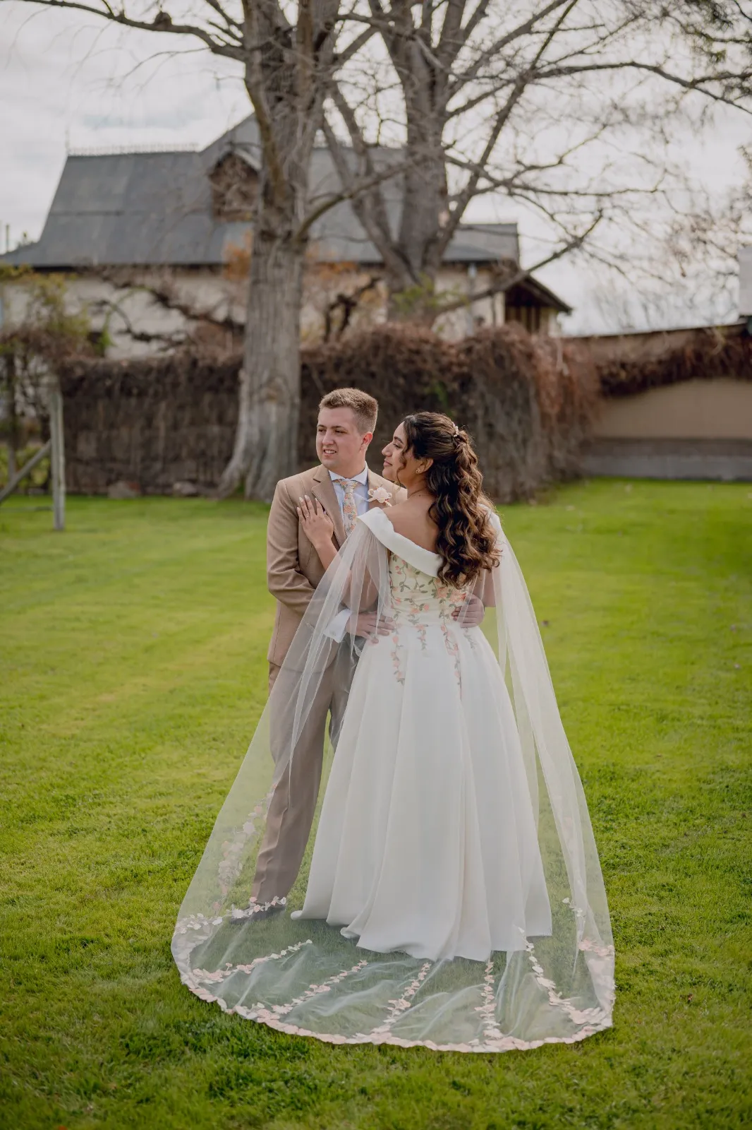 Novios sobre el césped, ella con un largo velo transparente