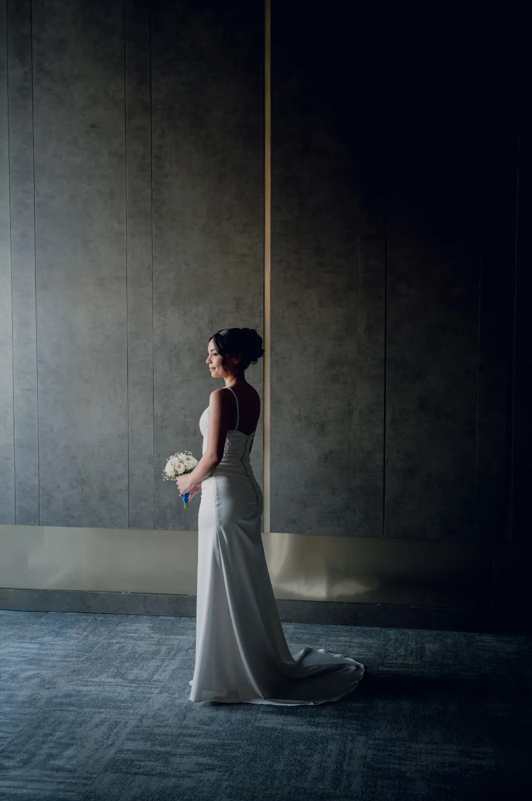 Novia de perfil en una sala sobria, con luz suave de ventana