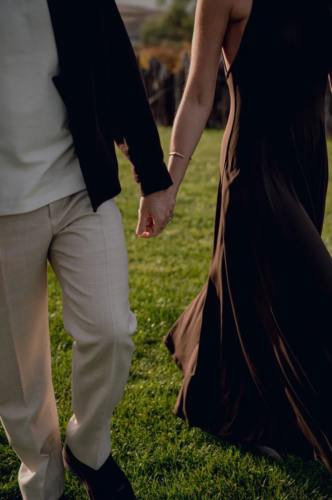 Detalle de una pareja caminando de la mano sobre el pasto