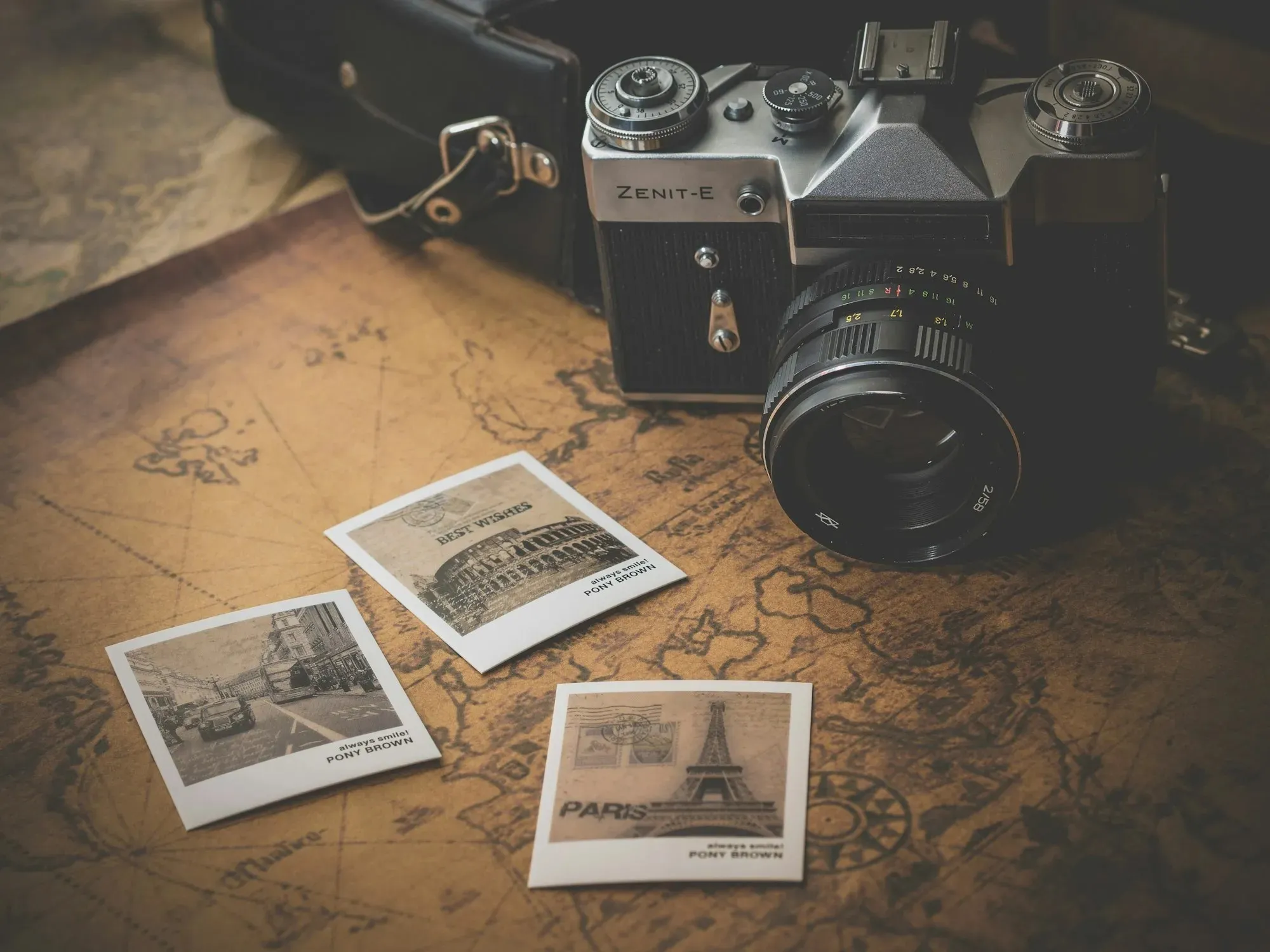 Cámara de fotos analógica sobre un mapa antiguo con fotos instantáneas